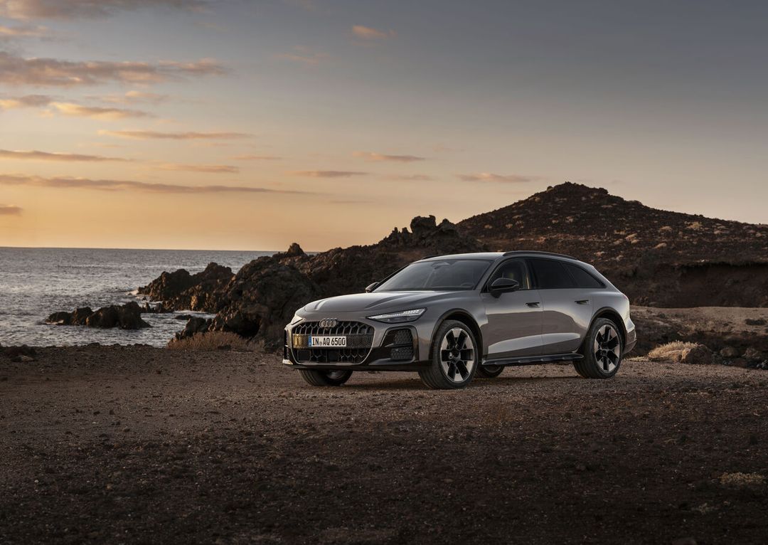 Audi A6 allroad C9 — ujęcie 3/4 z przodu, parkowanie na skalnym wybrzeżu o zachodzie słońca