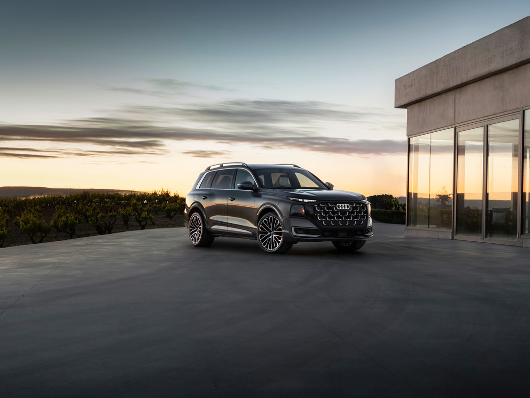 Audi Q9 — przód i bok, nowoczesna rezydencja o zachodzie słońca