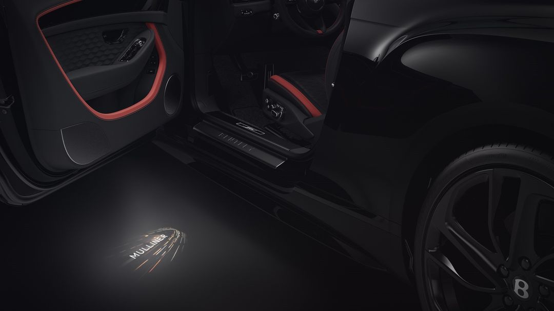 Bentley Mulliner — detal progu z podświetlanym logo „Mulliner”, czerwone wykończenie wnętrza
