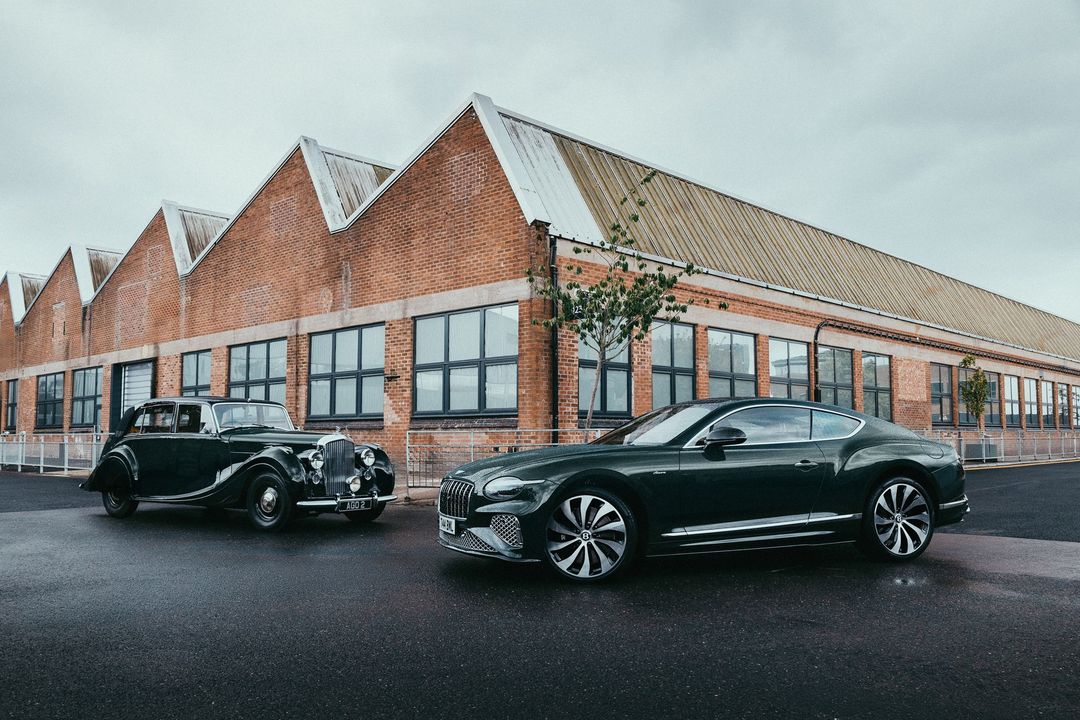 Bentley Continental GT Azure w profilu obok zabytkowego Bentleya, dramatyczne niebo nad fabryką w Crewe
