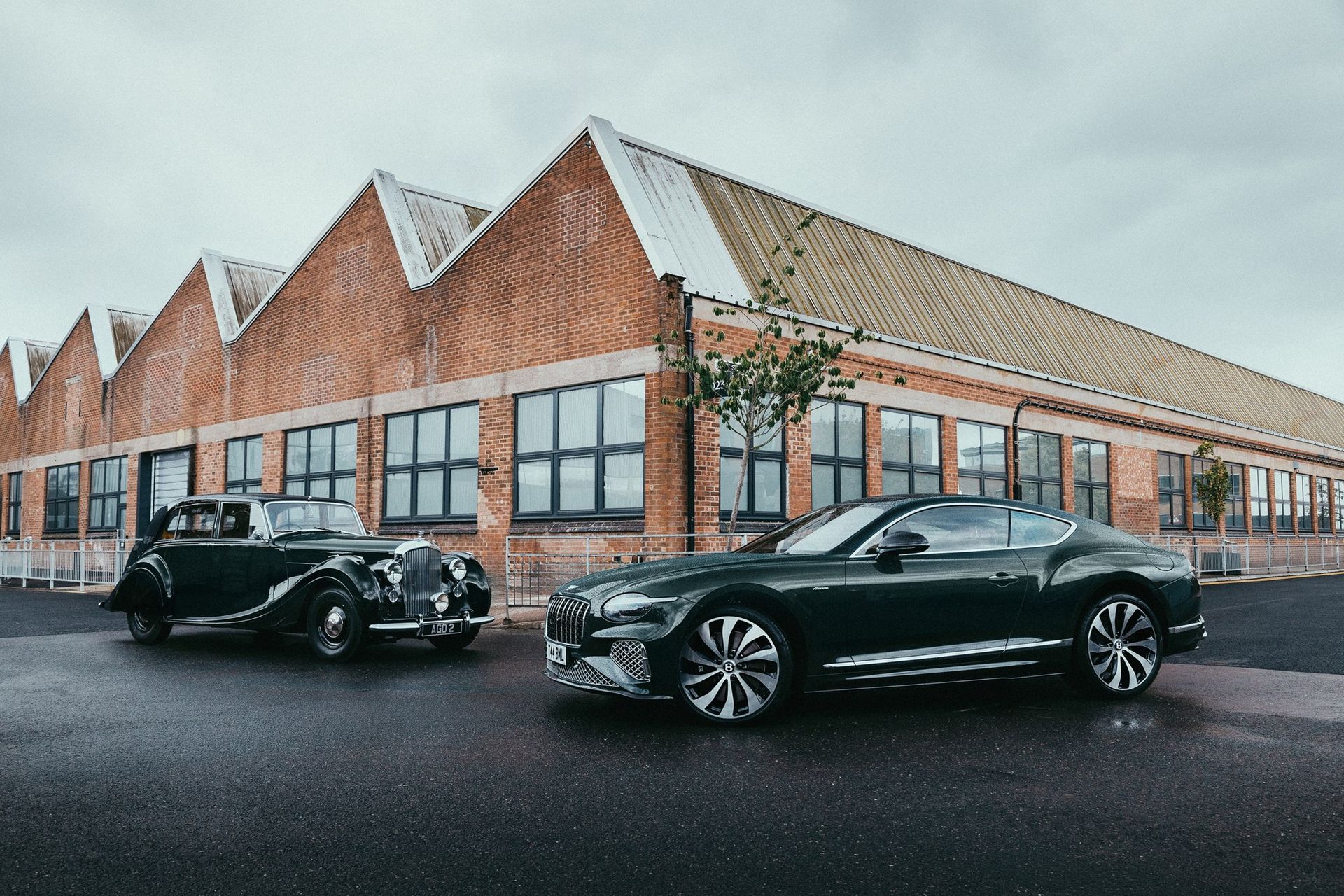 Bentley Continental GT Azure w profilu obok zabytkowego Bentleya, dramatyczne niebo nad fabryką w Crewe