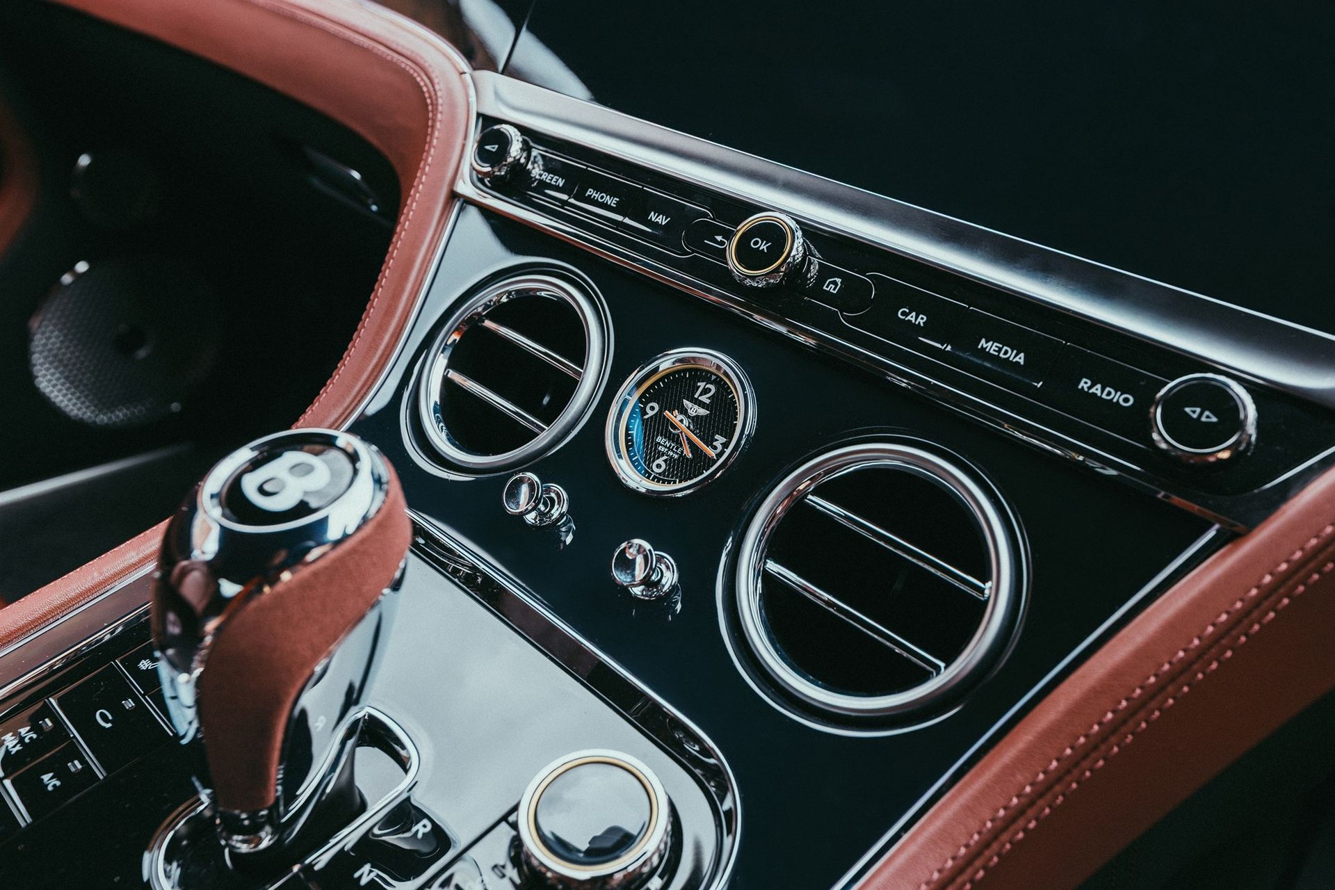 Bentley Continental GT Azure - detal konsoli środkowej z zegarem analogowym i pokrętłami