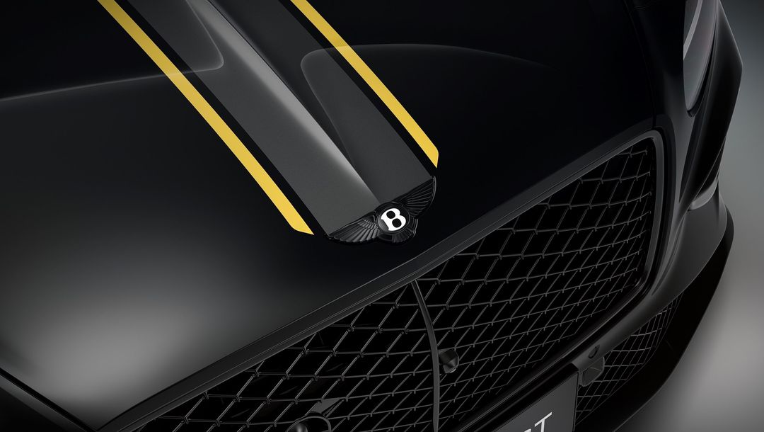Bentley Continental GT Mulliner - detal maski z żółtymi pasami wyścigowymi i logo skrzydła
