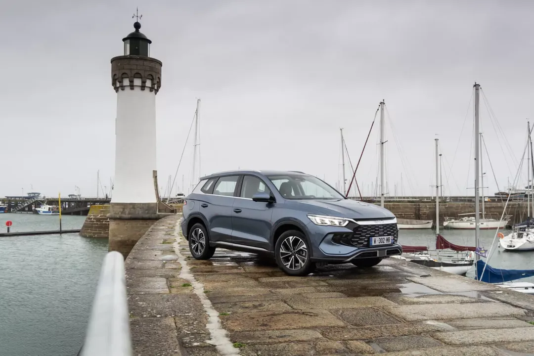 BYD SEALION 5 DM-i — bok z przodu 3/4 w kolorze szaroniebieskim, postój przy latarni morskiej w porcie jachtowym