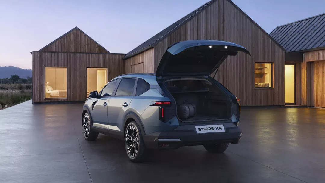 Dacia Striker — tył, otwarty bagażnik z bagażem przy drewnianym domu