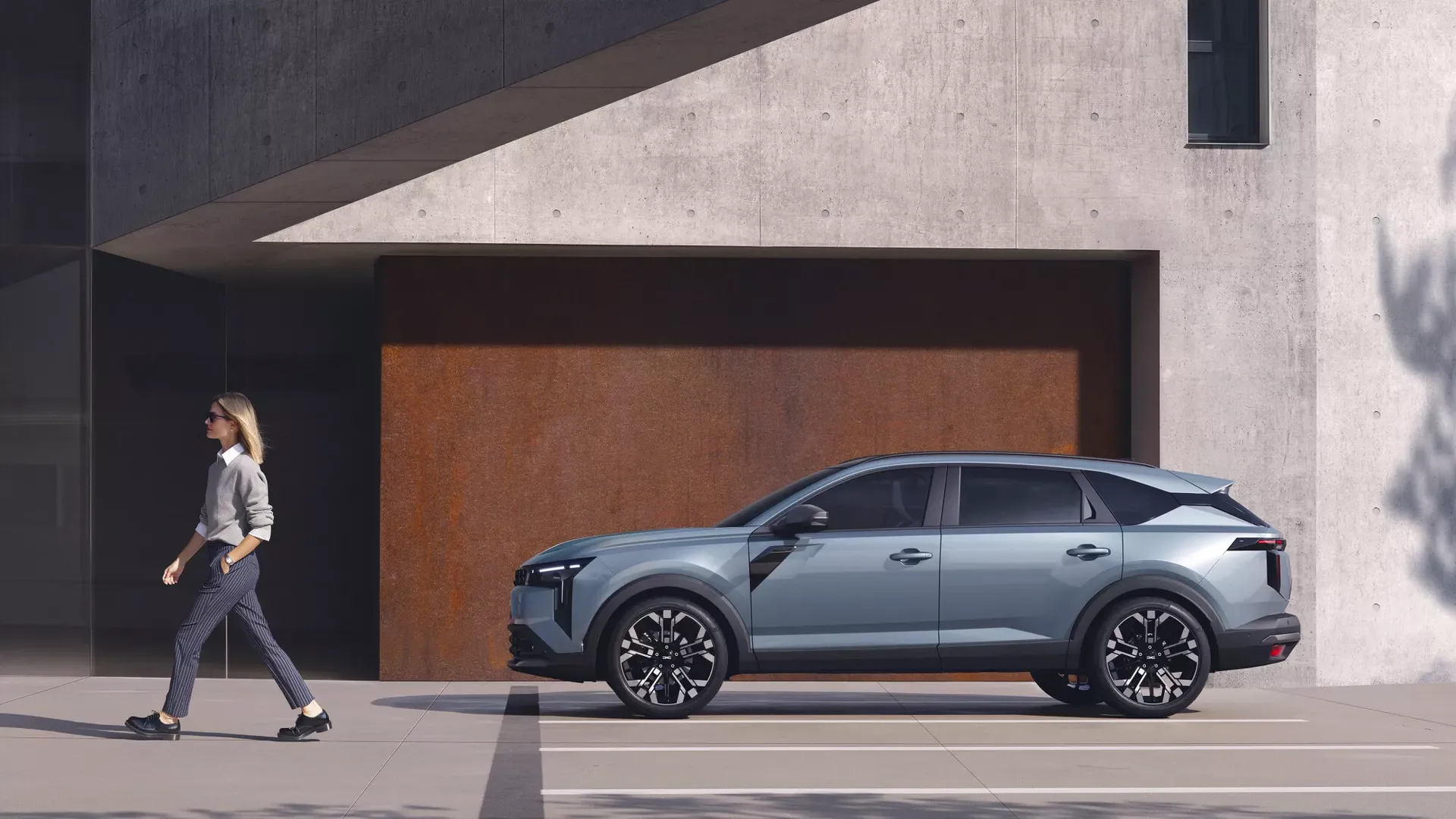 Dacia Striker — bok, kobieta przechodząca obok zaparkowanego auta