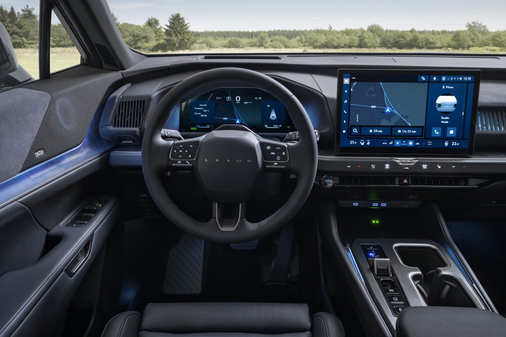 Lexus TZ — kokpit, ujęcie czołowe, kierownica po lewej (LHD), niebieskie wnętrze, w tle pejzaż zielonych pól