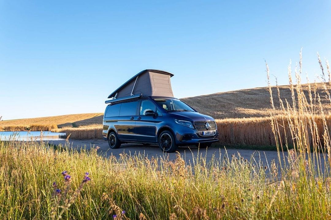 Mercedes-Benz Marco Polo — widok 3/4 przód, kamper z uniesionym dachem sypialnym nad jeziorem o zachodzie słońca