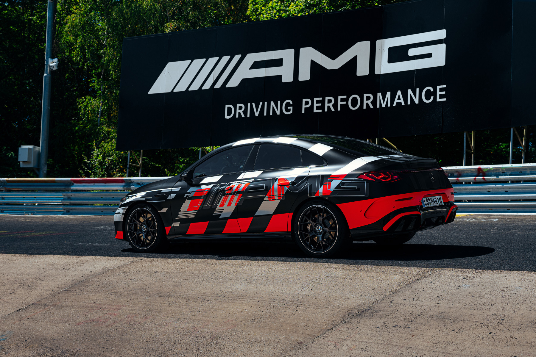 Mercedes-AMG CLA 45 — bok, na tle bandy toru i banera AMG Driving Performance