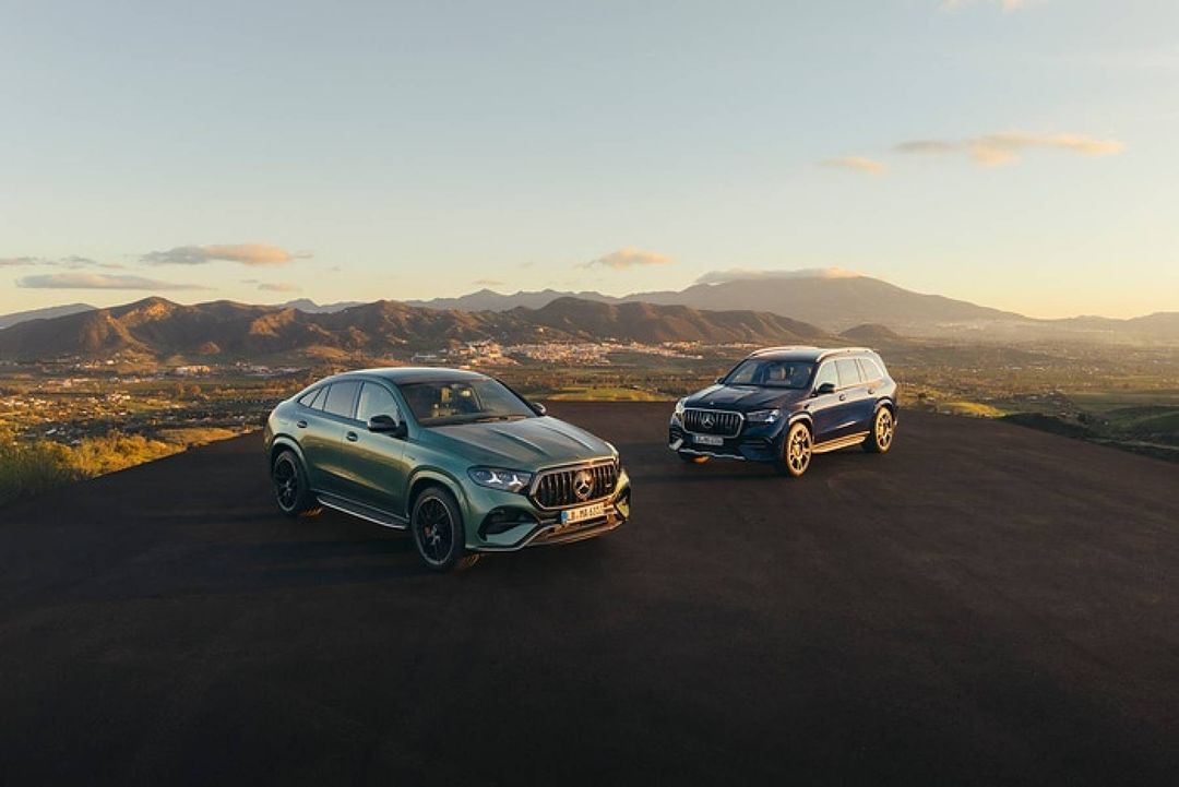 Mercedes-AMG GLE 63 S Coupé (zielony) i GLS 63 (granatowy) obok siebie na wulkanicznym płaskowyżu, w tle góry o zachodzie słońca