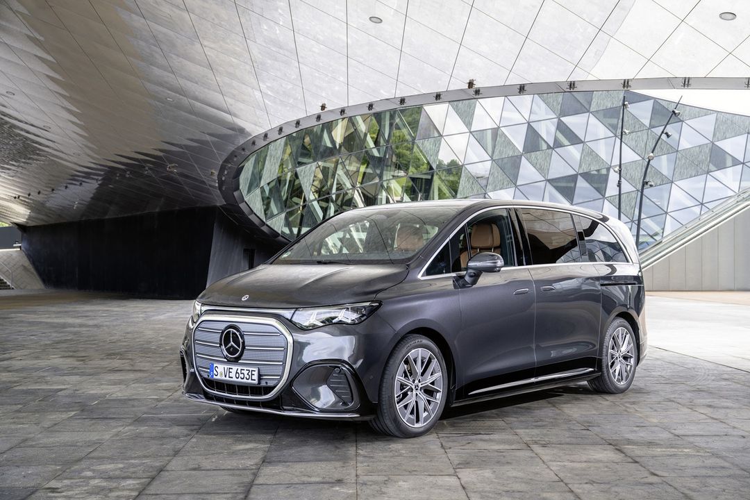 Mercedes-Benz VLE — przód i bok, ujęcie 3/4 przed nowoczesną architekturą szklaną