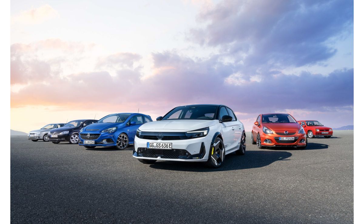 Opel Corsa GSE — przód, biały hatchback na tle rzędu poprzednich generacji modelu Corsa