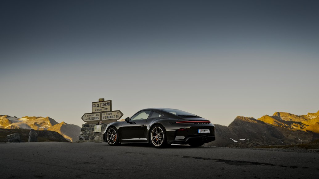 Porsche 911 GT3 Bergsport — trzy czwarte z tyłu przy tabliczce Col de l’Iseran o zmierzchu