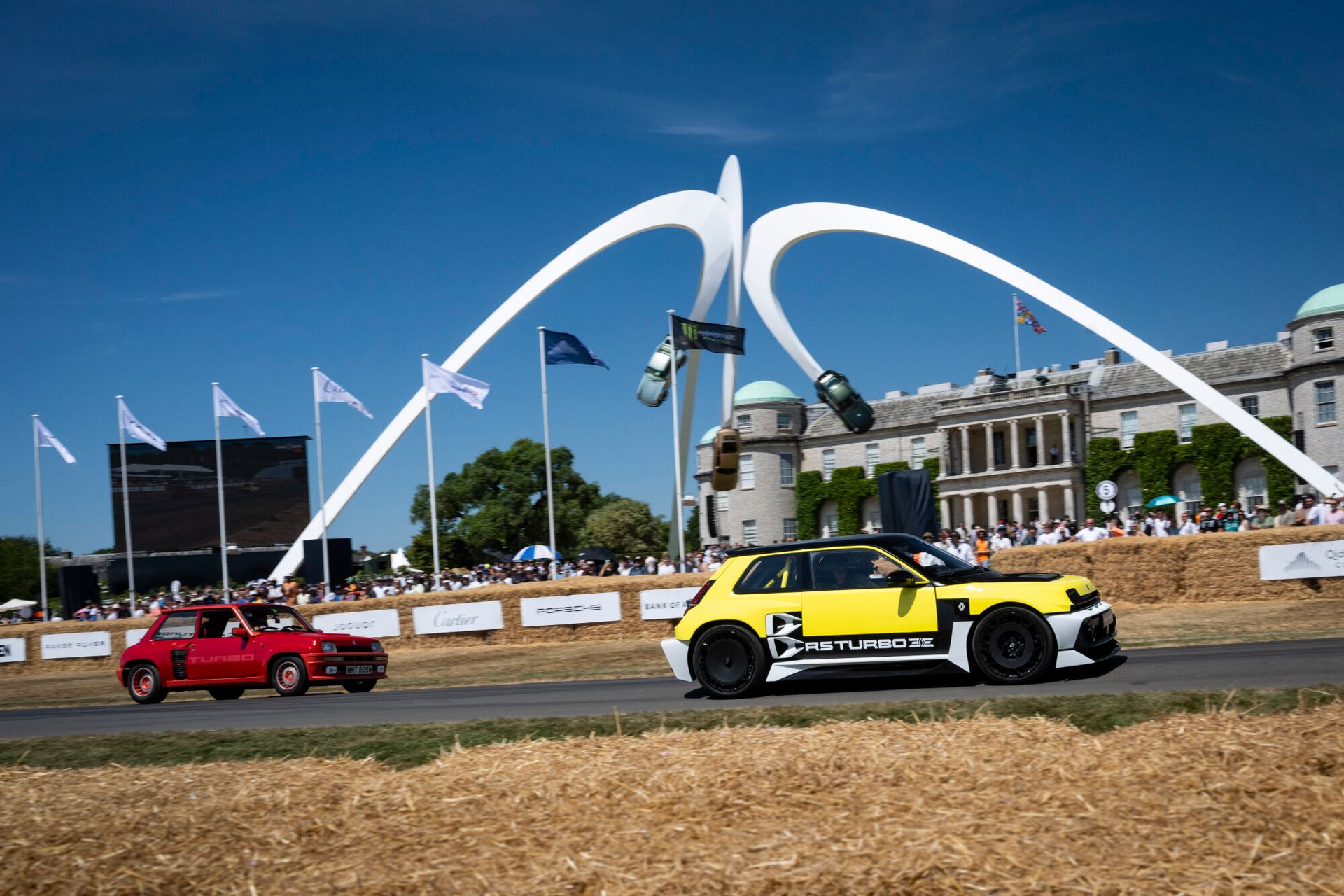 Renault 5 Turbo 3E — żółty prototyp na torze Goodwood, w tle łuk Trophy i tłum widzów