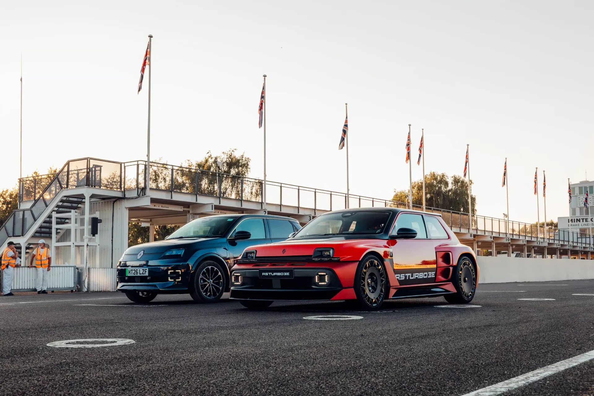 Renault 5 Turbo 3E (czerwony) obok innego modelu Renault — przód, brytyjskie flagi w tle na torze Goodwood