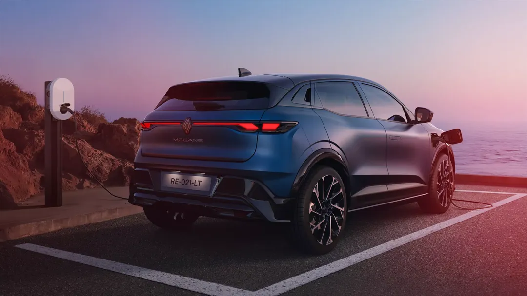 Renault Megane E-Tech Electric — tył/bok, ładowanie przy stacji nad morzem o zmierzchu