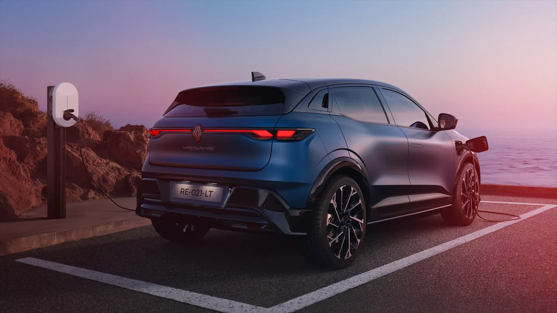 Renault Megane E-Tech Electric — tył/bok, ładowanie przy stacji nad morzem o zmierzchu