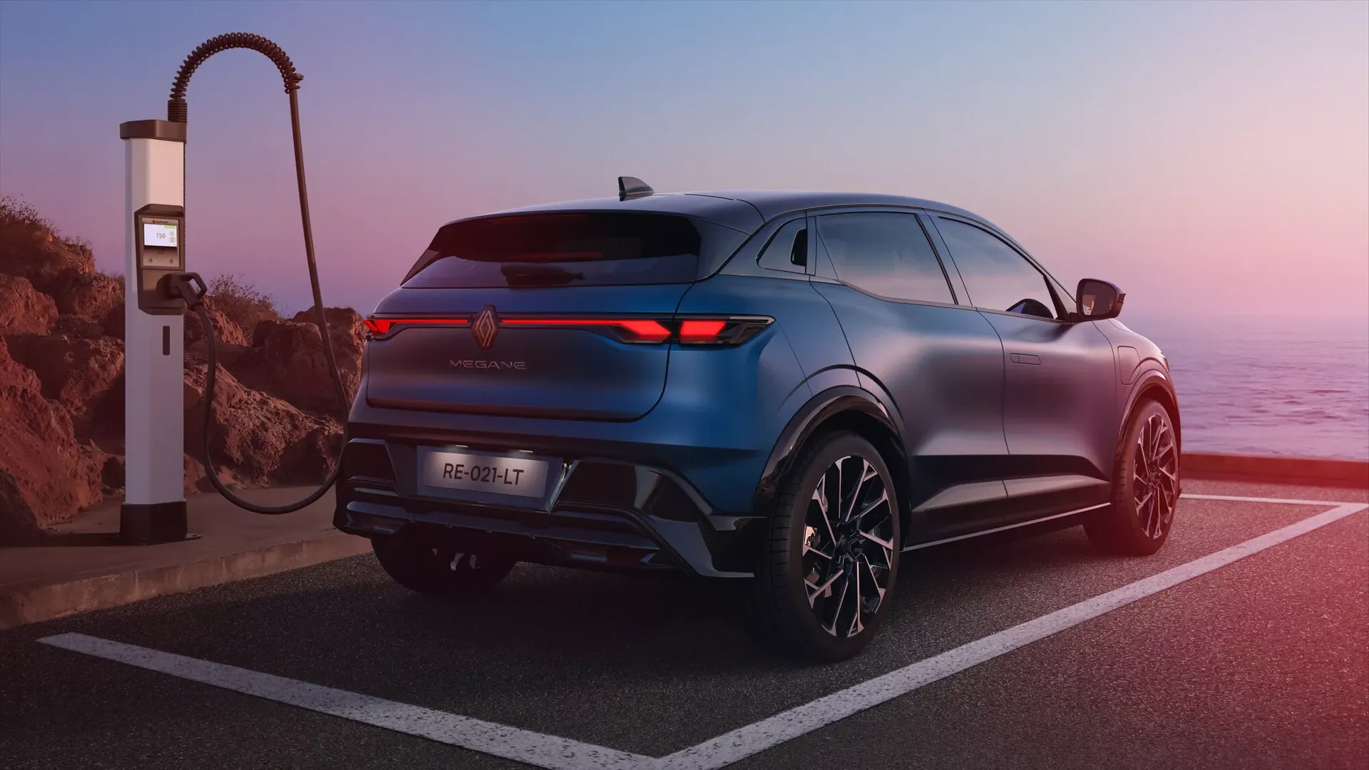 Renault Megane E-Tech Electric — tył/bok, ładowanie przy stacji nad morzem, ujęcie alternatywne