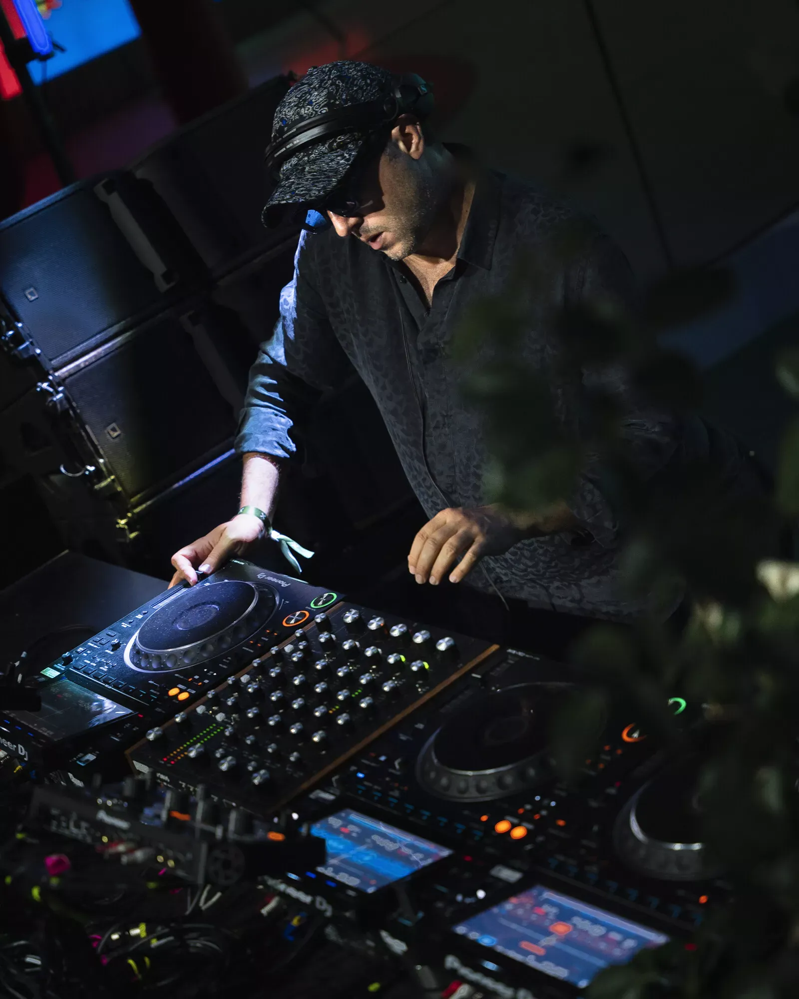 Renault — DJ w kapeluszu i okularach przy konsolecie, ciemna, klimatyczna scena z zielenią w kadrze