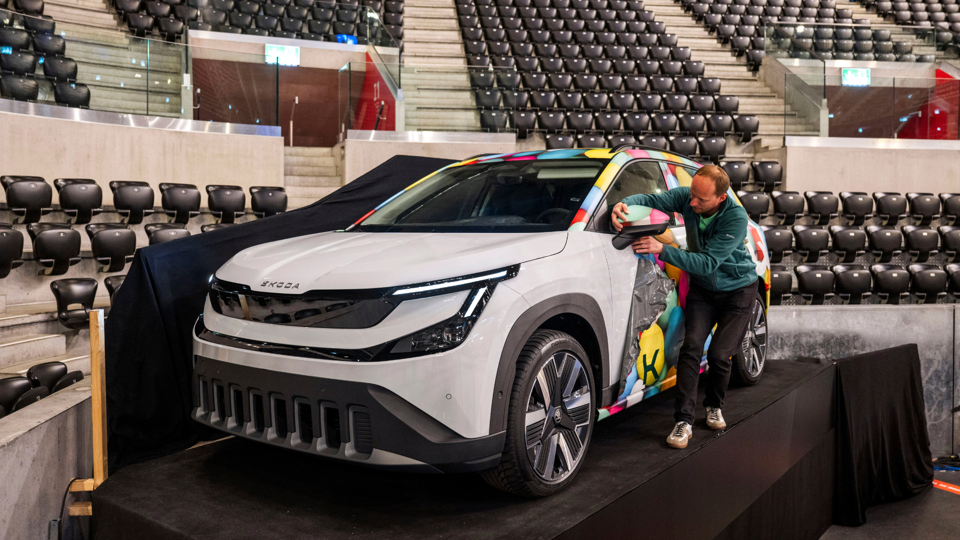 Škoda Epiq — artysta maluje egzemplarz art car na scenie w hali sportowej
