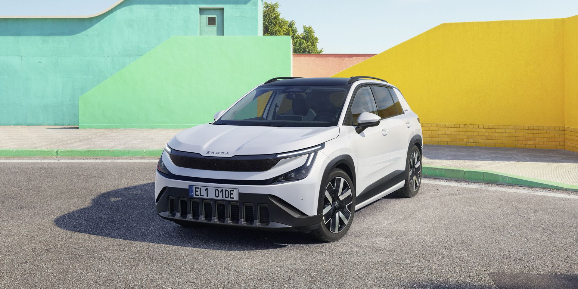 Škoda Epiq — przód 3/4, biały kolor, tło kolorowe ściany, oficjalna sesja prasowa
