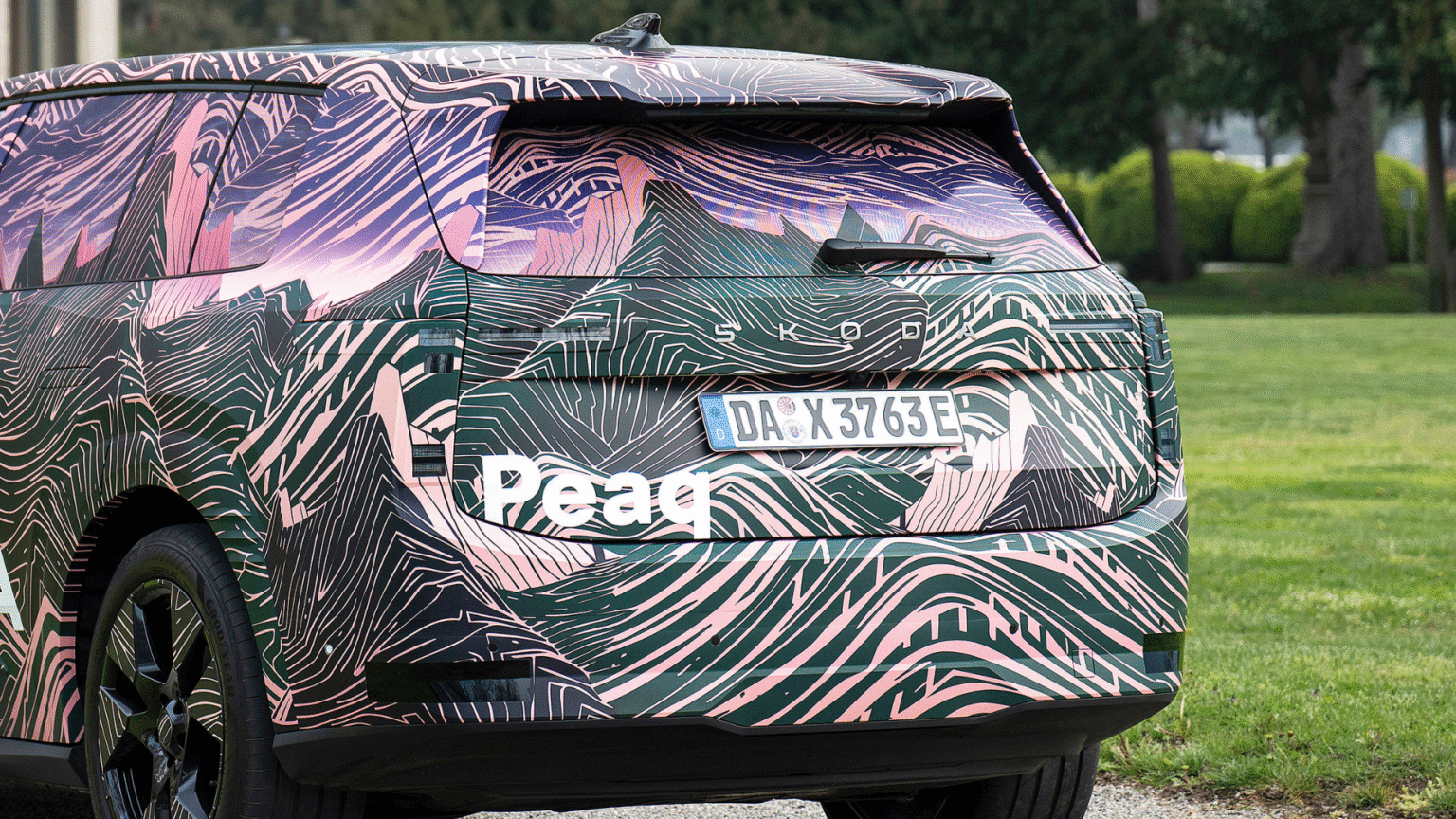 Škoda Peaq — tył pojazdu, napis promocyjny „Peaq” jako graficzna nakładka na zdjęcie, postój na trawniku