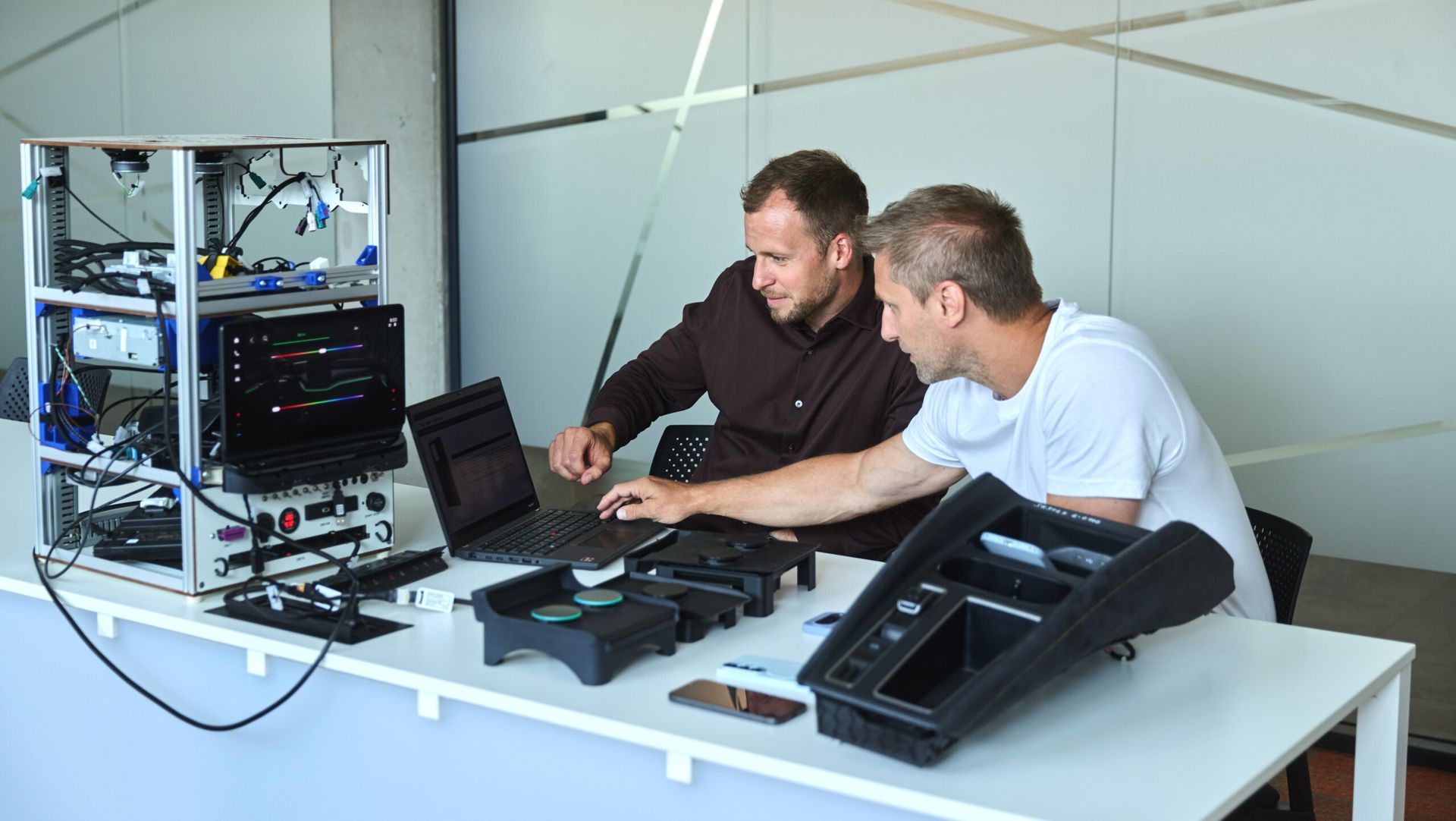 Inżynierowie Škody analizują na laptopie dane z testów ładowarki Qi2