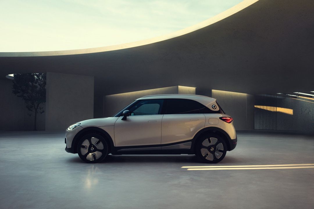 smart – bok, białe auto na dziedzińcu z betonową architekturą