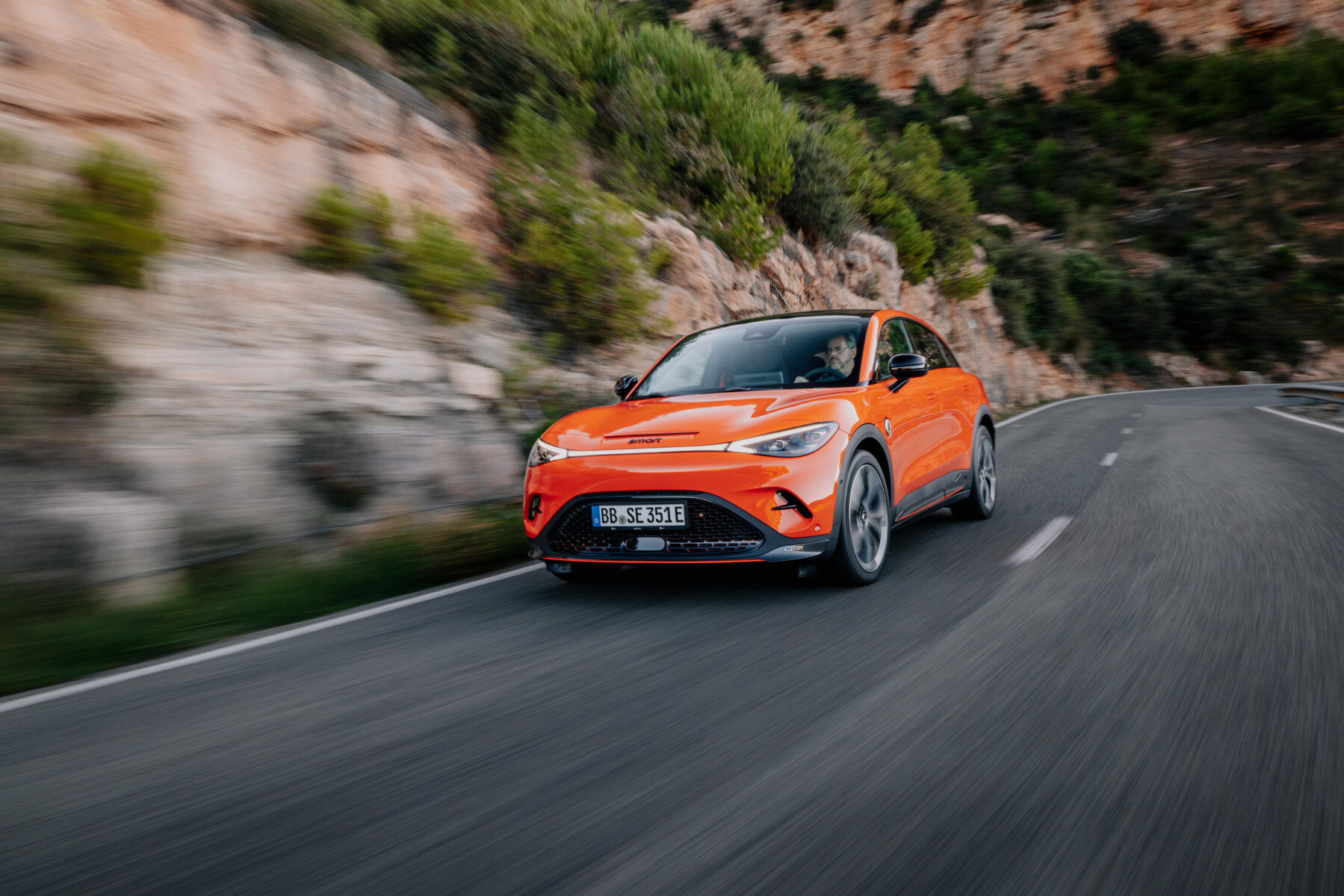 smart #2 – przód, pomarańczowe auto w dynamicznej jeździe górską drogą