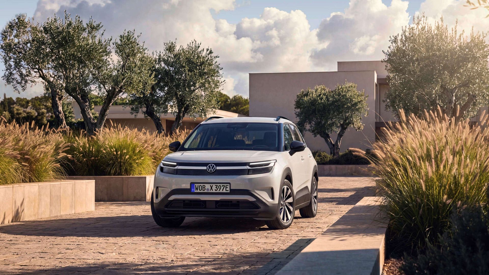 Volkswagen ID. Cross — przód, stojący na posesji z widokiem na dom i roślinność (najwyższa rozdzielczość)